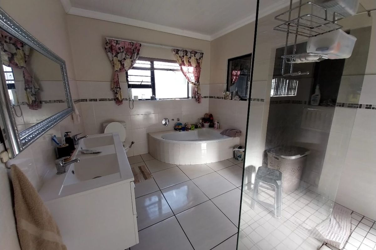 Spacious bathroom featuring a double vanity, a built-in bathtub, and a separate glass-enclosed shower with tiled finishes throughout.