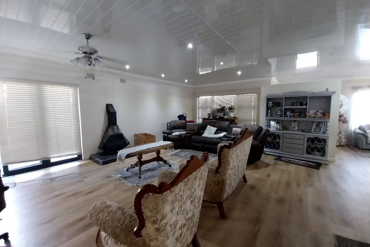 Spacious living room featuring a freestanding fireplace, modern laminate flooring, recessed lighting, and a glossy ceiling finish with integrated ceiling fan.