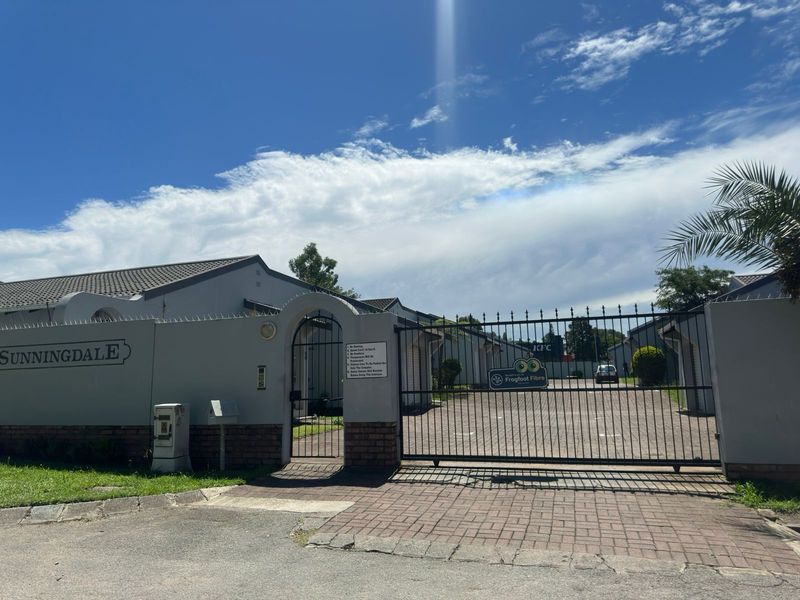 Front entrance view of the Sunningdale complex featuring a secure gated access point, paved driveway, and perimeter walling.