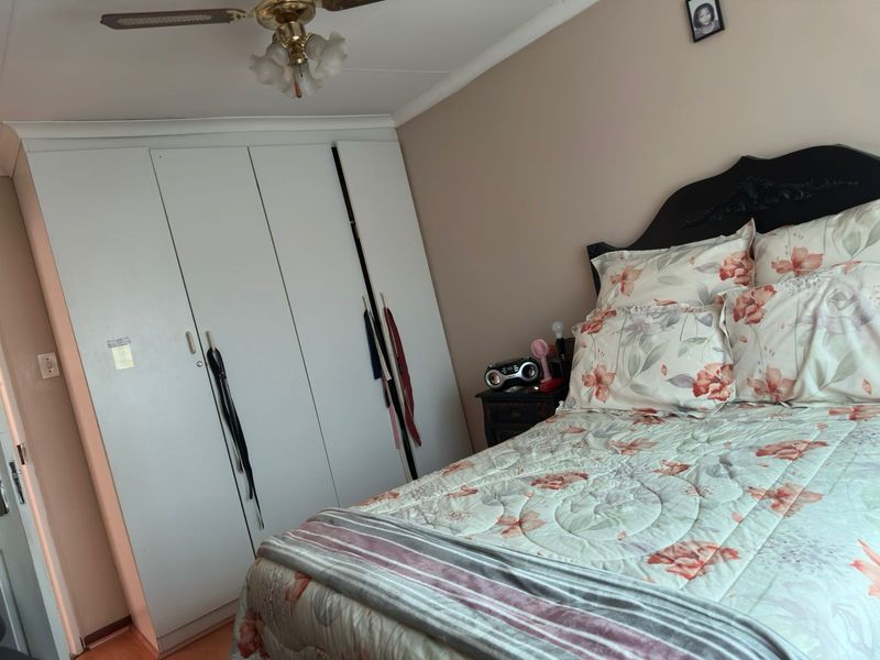 A bedroom featuring built-in cupboards and a ceiling fan, providing functional storage and climate control.