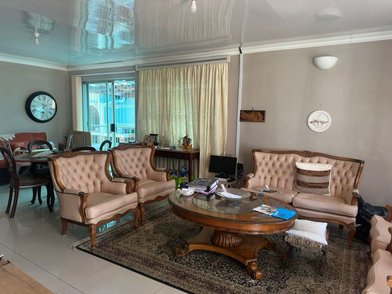 A spacious living room featuring glossy ceiling finishes, tiled flooring, and a sliding glass door providing natural light.