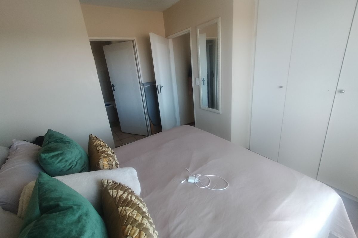 A bedroom featuring built-in cupboards and access to adjacent rooms, providing a functional and neutral living space.