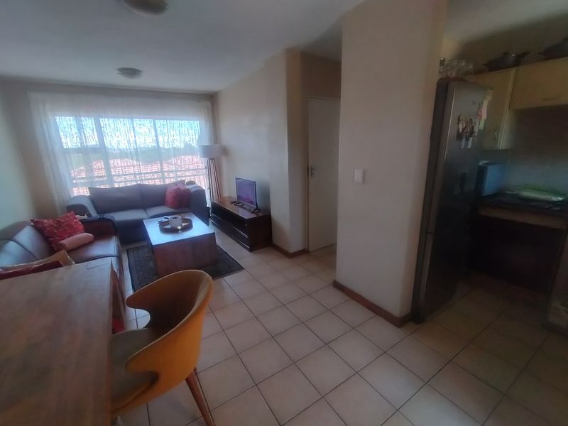 Open plan living and kitchen area featuring tiled flooring and direct access to a balcony through a sliding door.
