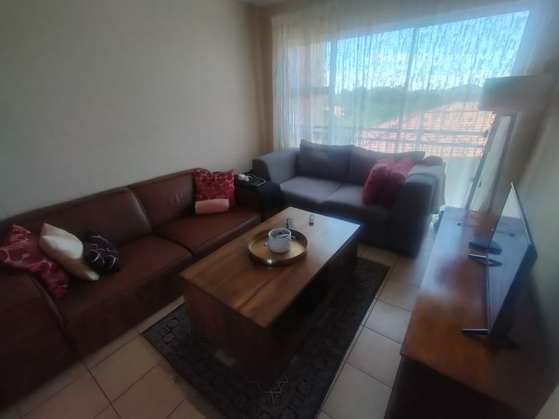A comfortable living room featuring tiled flooring and a large sliding glass door that provides natural light and access to the balcony.