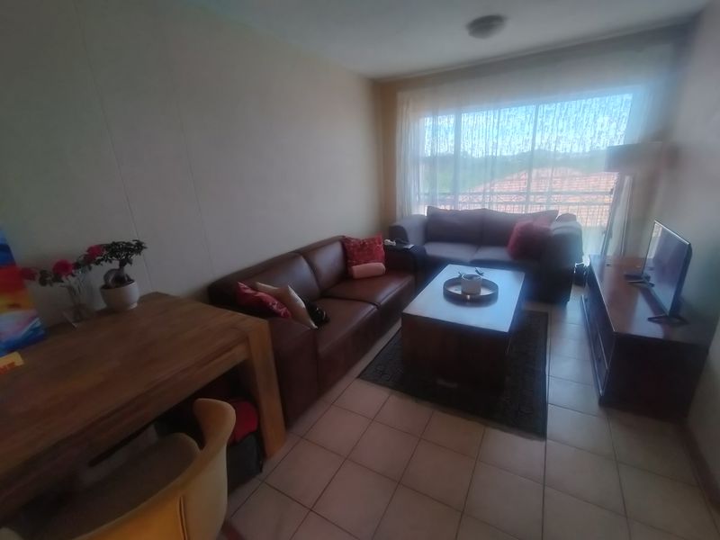 A comfortable living room featuring tiled flooring and a large window that allows for natural light.