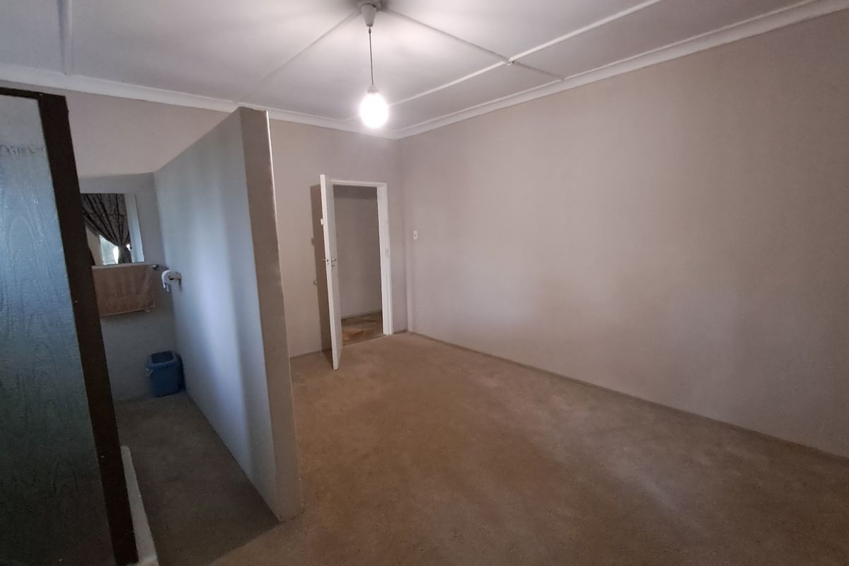 An empty bedroom featuring a partition wall, coved ceiling, and neutral wall tones, offering a blank canvas for potential interior design updates.