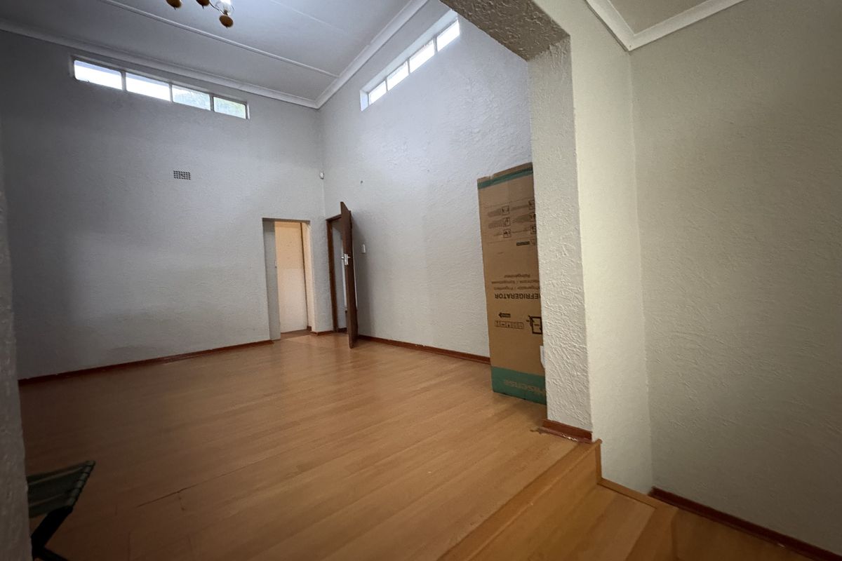 Spacious living area featuring high ceilings with clerestory windows, laminate wood flooring, and a split-level layout.