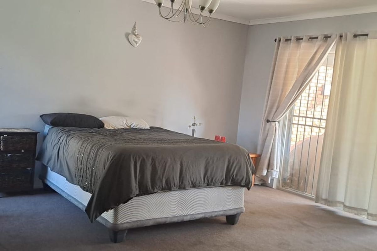 Spacious bedroom featuring carpeted flooring and a sliding glass door with security gate providing direct access to the outdoor area.