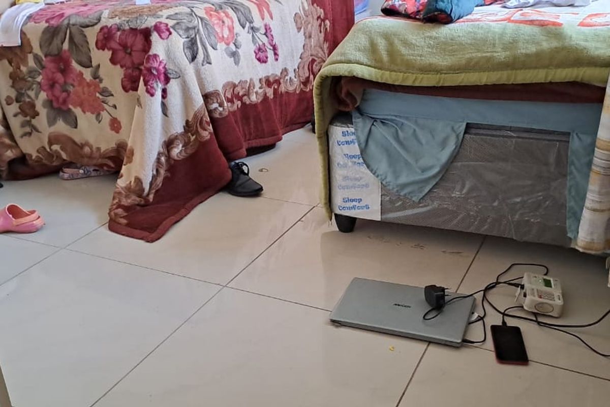 A bedroom featuring tiled flooring and standard electrical fixtures.