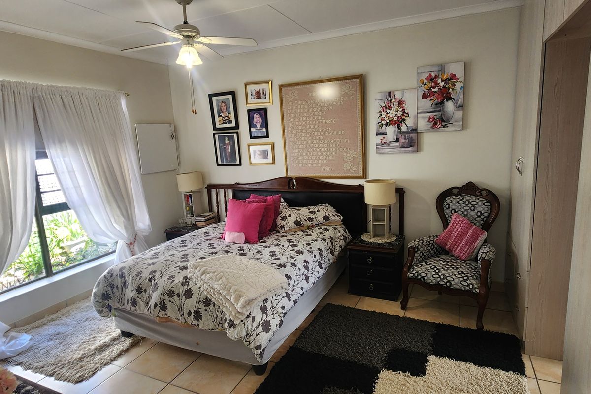 A well-lit bedroom featuring tiled flooring, a ceiling fan, and built-in wardrobe cabinetry.