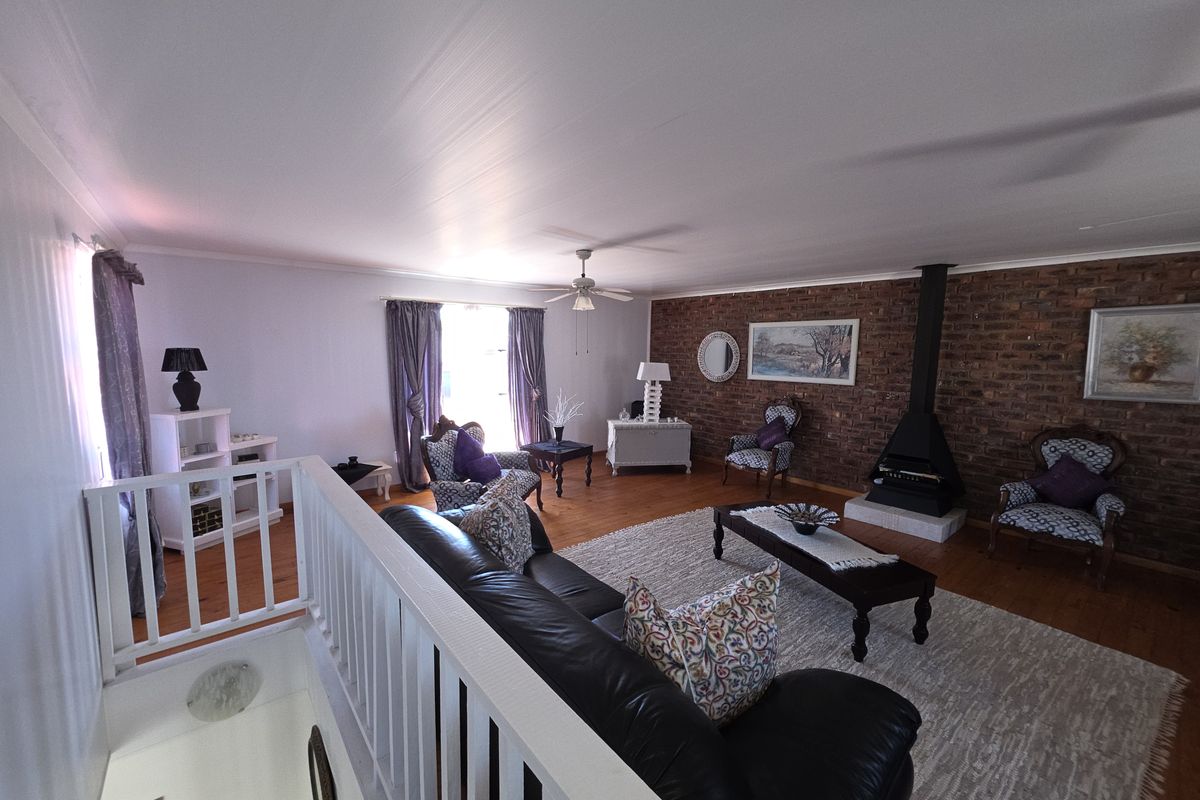 Spacious living room featuring a prominent exposed brick feature wall, a built-in fireplace, and polished timber flooring, overlooking the lower level via a balustrade.