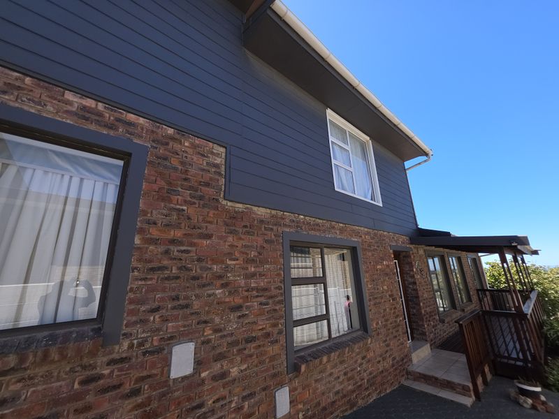 A view of the property exterior featuring a combination of face brick and dark horizontal cladding with aluminium window frames.