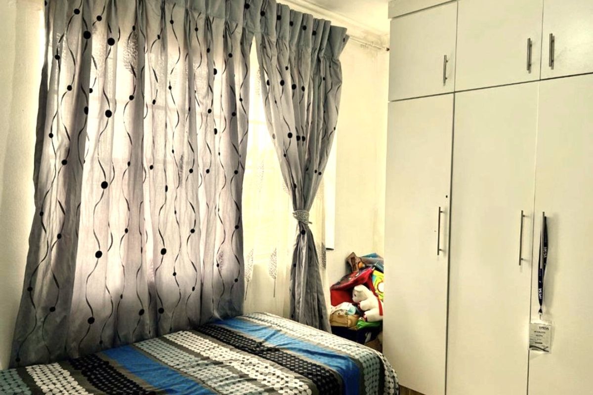 A bedroom featuring built-in white cabinetry and a window with curtains.