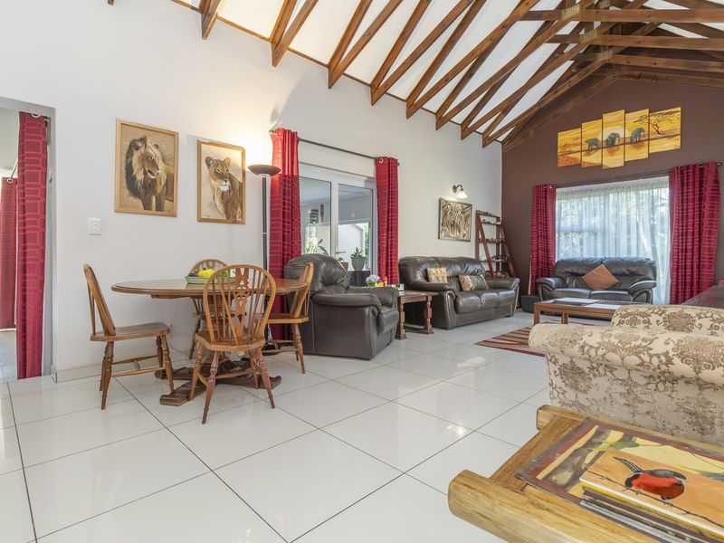 Spacious open-plan living and dining area featuring high vaulted ceilings with exposed timber rafters and polished porcelain floor tiles.