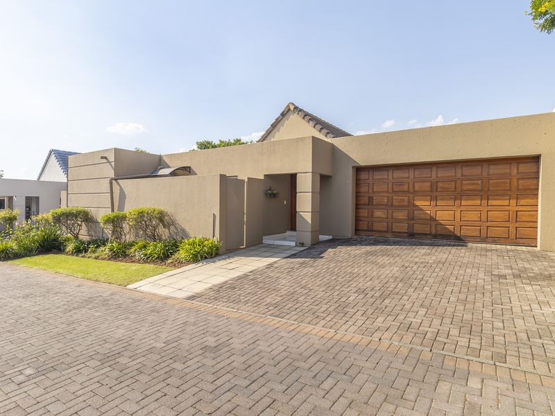 Front elevation of a modern house featuring a paved driveway, a wooden sectional garage door, and a neat landscaped garden bed.