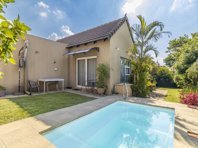 A well-maintained rear garden area featuring a private swimming pool, paved surround, and direct access to the home via sliding glass doors.