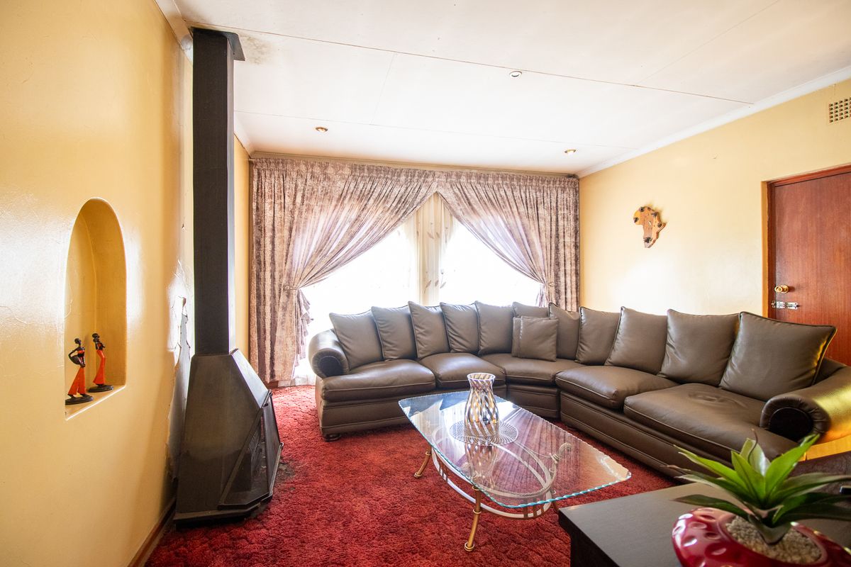 Living room featuring a freestanding fireplace, recessed wall niche, and carpeted flooring, offering a cozy space with potential for modern updates.