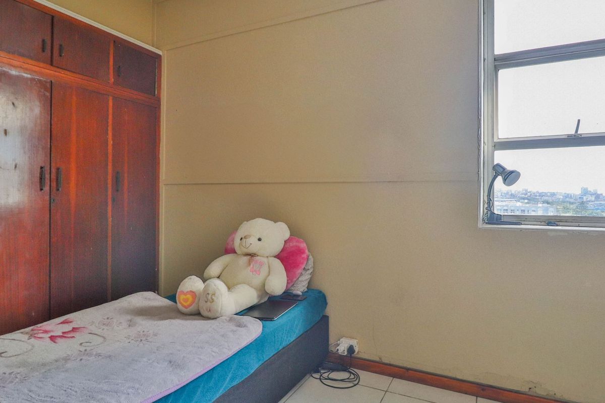 A bedroom featuring a built-in wooden wardrobe, tiled flooring, and a window with city views.