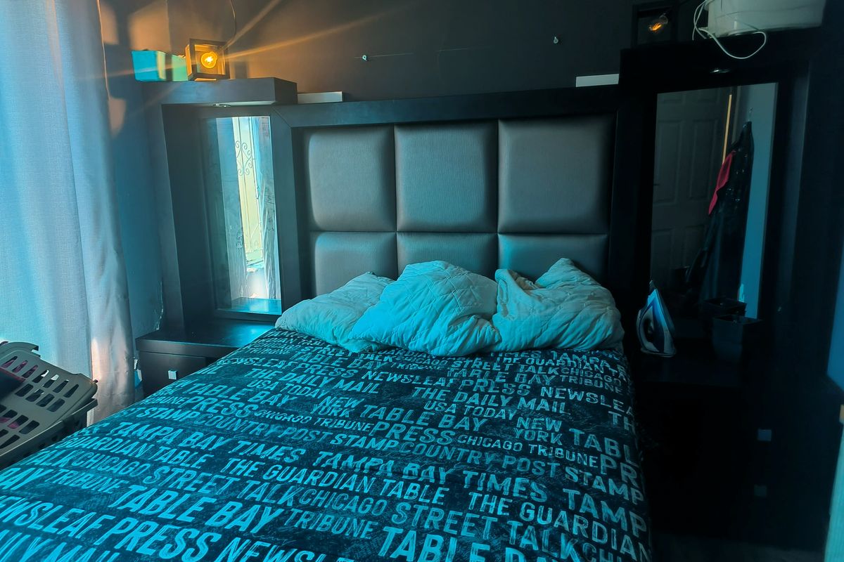 A bedroom featuring a built-in headboard with integrated side shelving and mirror panels.