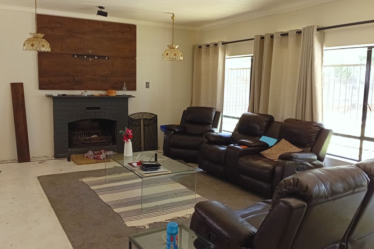 A living room featuring a brick fireplace with a wood-paneled accent wall and large windows providing natural light.