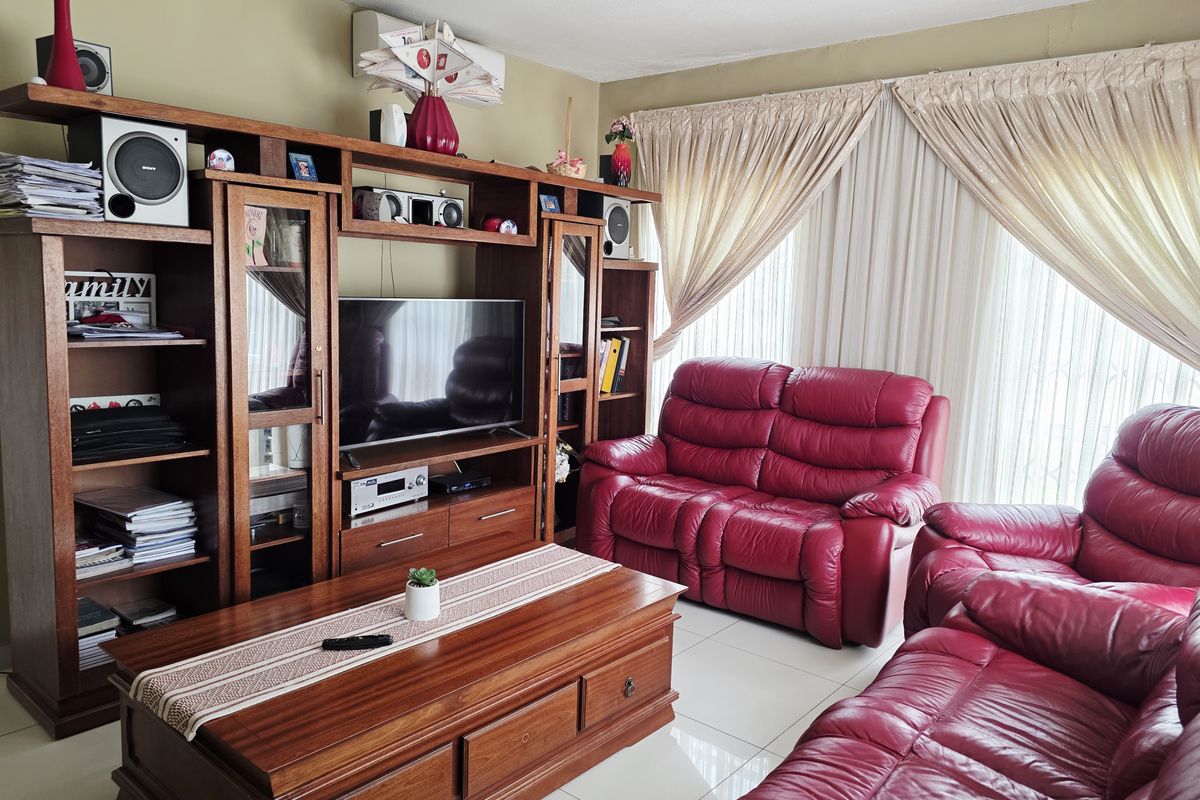 A living room featuring tiled flooring and a wall-mounted air conditioning unit, with large windows dressed in curtains.