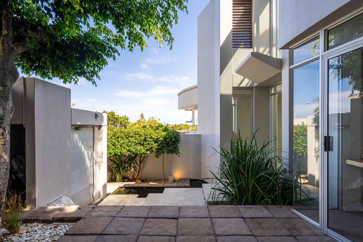 A modern rear courtyard featuring a paved patio, a small water feature, and large sliding glass doors providing seamless indoor-outdoor flow.