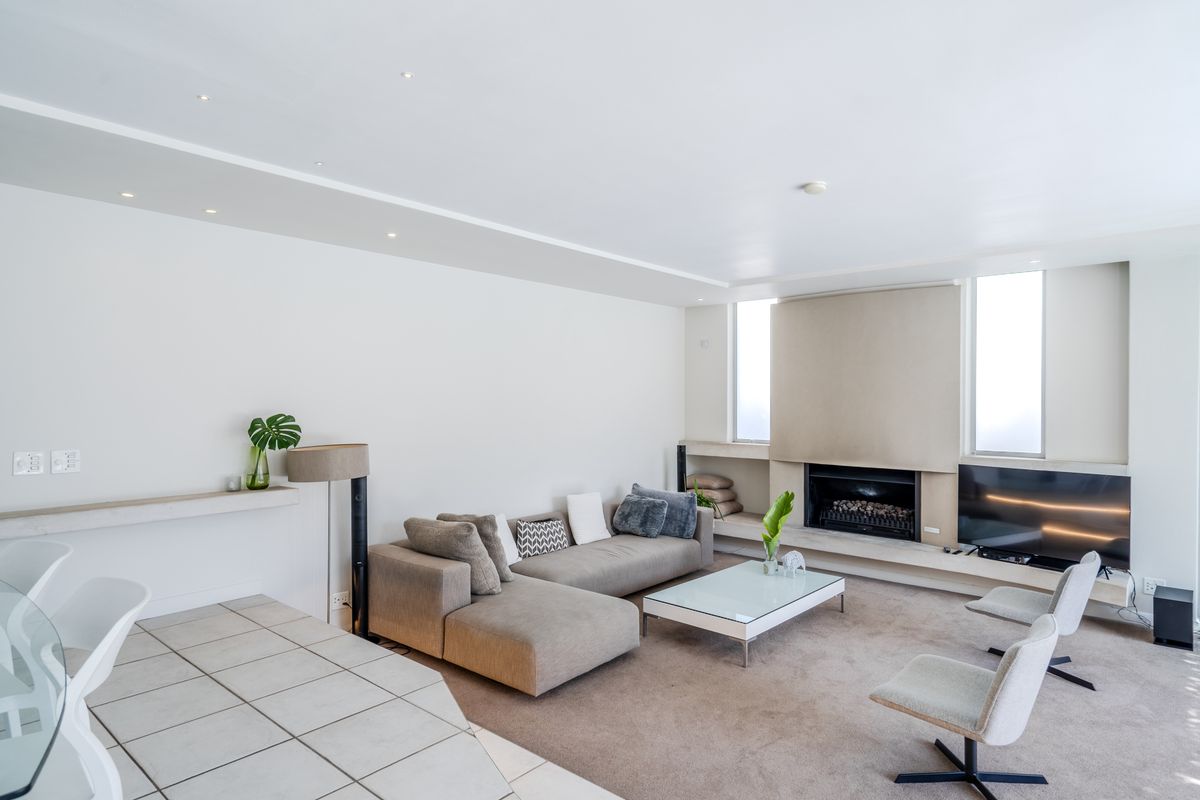 Spacious living room featuring a built-in fireplace, recessed lighting, and a combination of tiled and carpeted flooring.