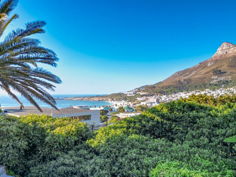 A scenic elevated view overlooking the coastal landscape, ocean, and mountain range, showcasing the property's prime location and natural surroundings.