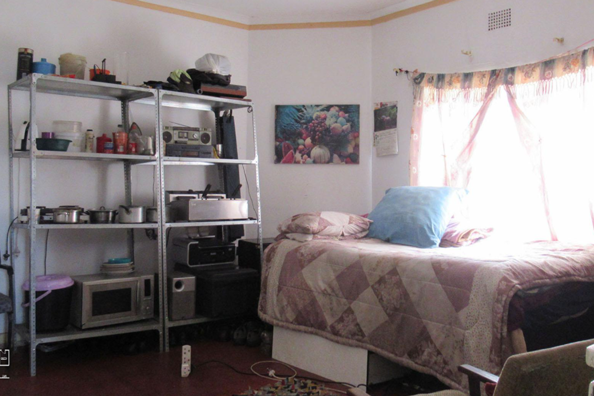 A bedroom featuring a large window with natural light, providing a functional space for rest and storage.