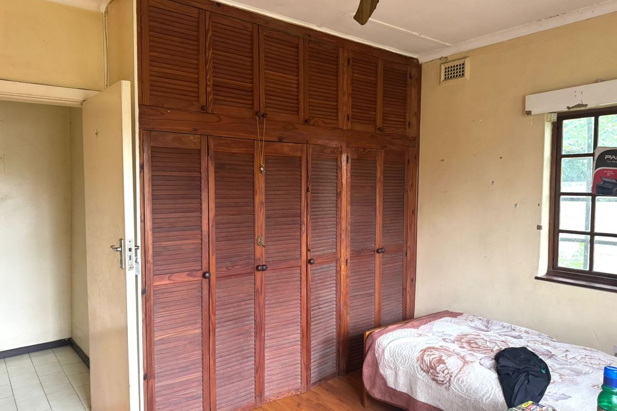 Bedroom featuring extensive built-in wooden cabinetry, laminate flooring, and a ceiling fan, offering a functional space with potential for cosmetic updates.