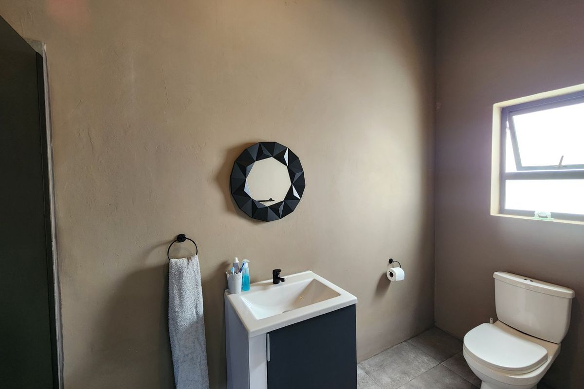 A functional bathroom featuring a modern vanity cabinet, basin, toilet, and tiled flooring with neutral wall finishes.