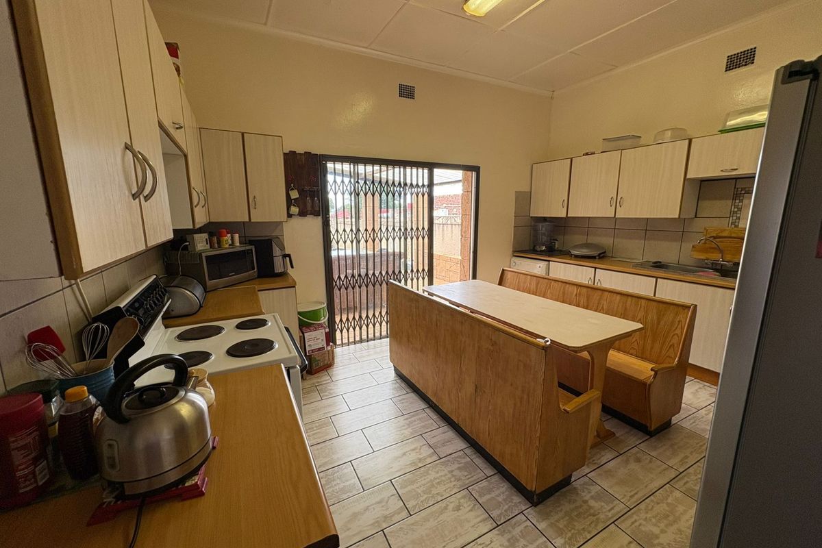 Functional kitchen featuring laminate cabinetry, built-in electric stove, tiled flooring, and direct access to the exterior via a security gate.