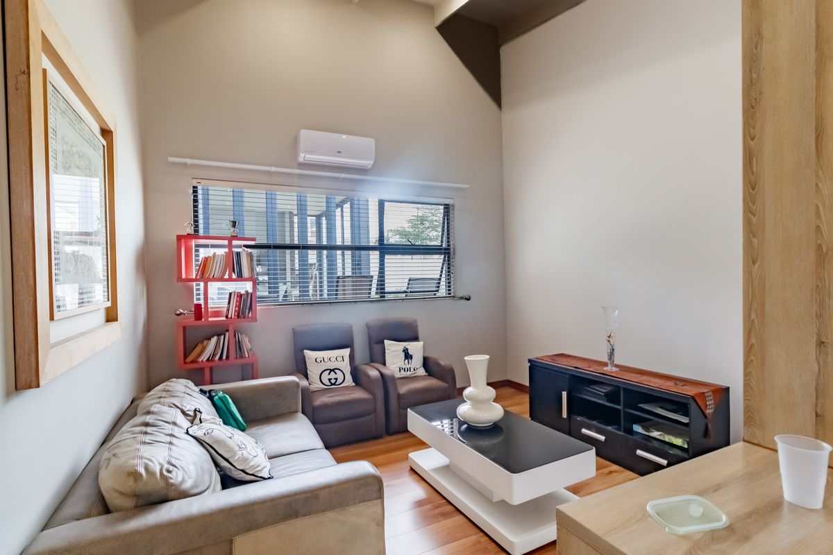 A bright living room featuring vaulted ceilings, timber flooring, and a wall-mounted split-system air conditioner.