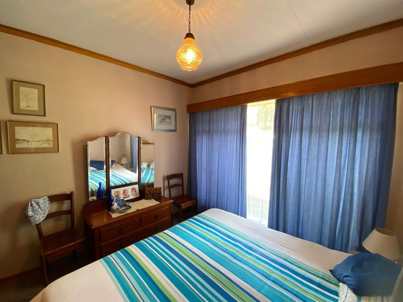 A bedroom featuring timber crown molding, a timber window pelmet, and a central pendant light fixture.