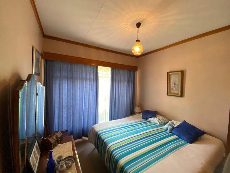 A bedroom featuring timber crown molding, a timber curtain pelmet, and a central pendant light fixture.