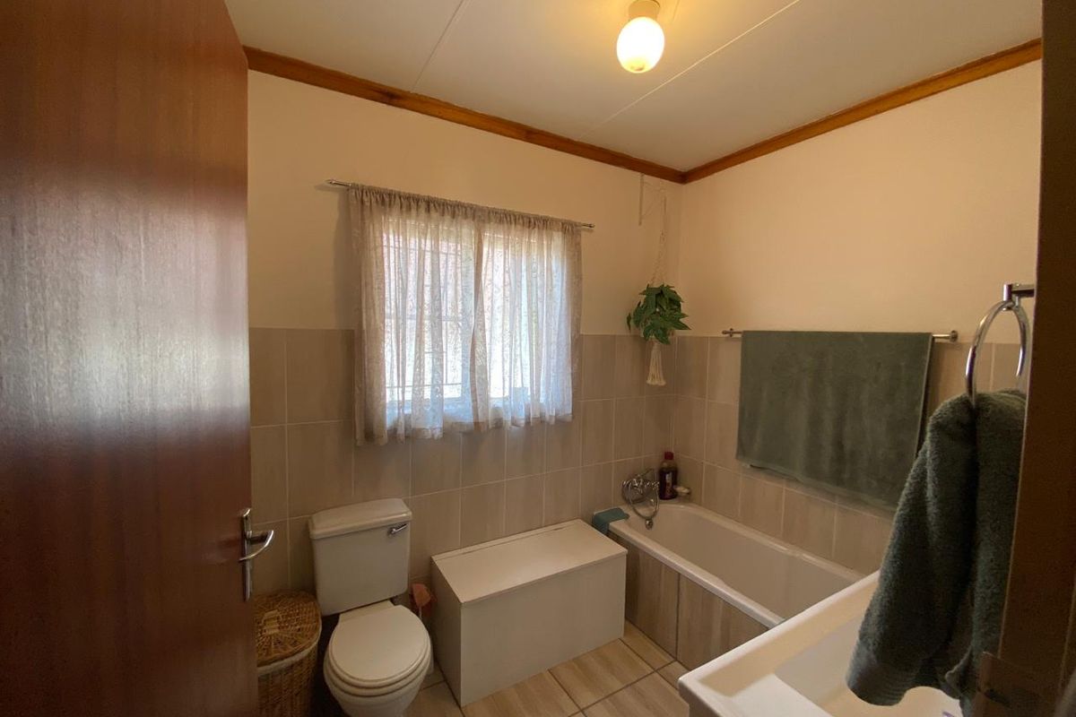 A functional bathroom featuring a bathtub, toilet, and neutral wall and floor tiling, offering a clean and practical space.