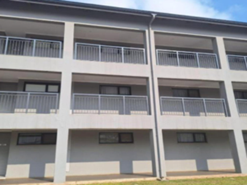 Exterior view of a multi-story apartment building featuring private balconies with metal railings and concrete structural columns.