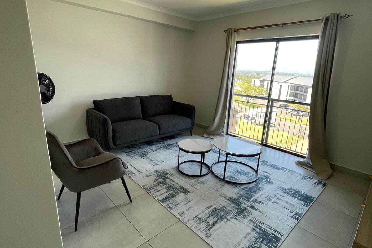 A bright living room featuring large sliding glass doors that open onto a balcony, providing natural light and views of the surrounding area.