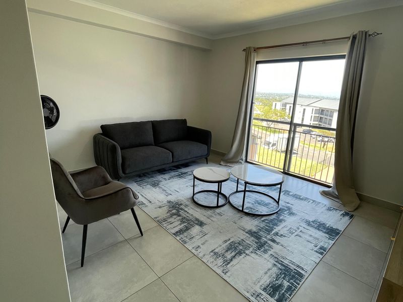 A bright living room featuring large sliding glass doors that open onto a balcony, providing natural light and views of the surrounding area.