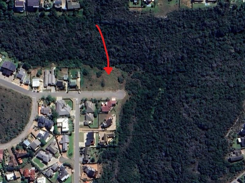 Aerial view of a vacant residential plot situated at the end of a cul-de-sac, bordered by dense natural vegetation.