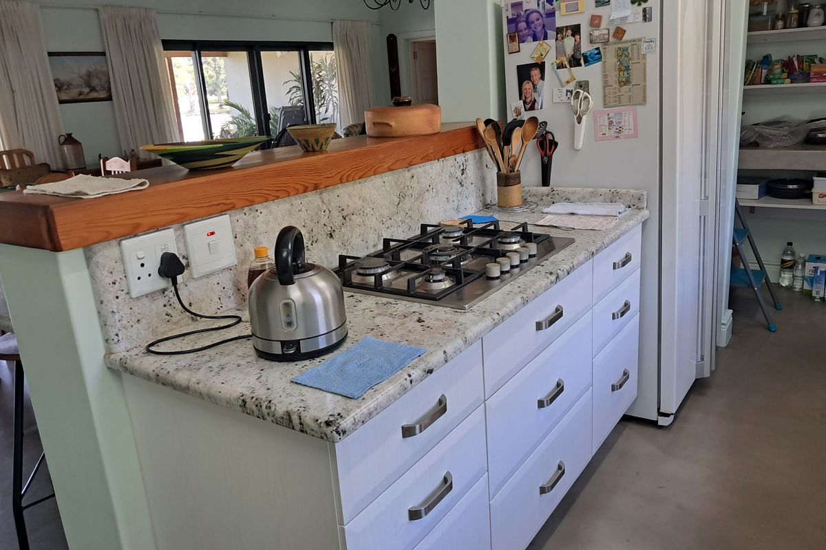 A functional kitchen featuring granite countertops, a gas cooktop, and ample built-in cabinetry, with an open-plan layout connecting to the living area.