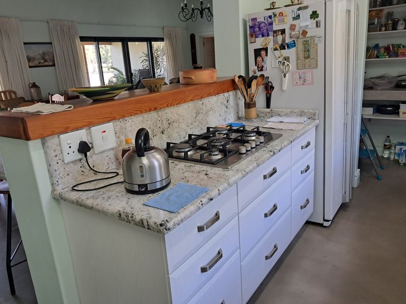 A functional kitchen featuring granite countertops, a gas cooktop, and ample built-in cabinetry, with an open-plan layout connecting to the living area.