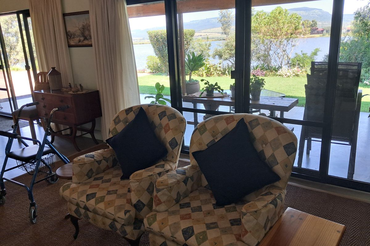 A bright living room featuring large sliding glass doors that provide expansive views of the garden and lake beyond.