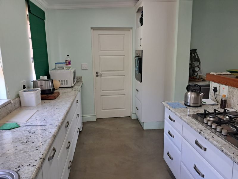 A functional kitchen featuring granite countertops, built-in cabinetry, a gas hob, and a built-in oven, complemented by durable concrete flooring.
