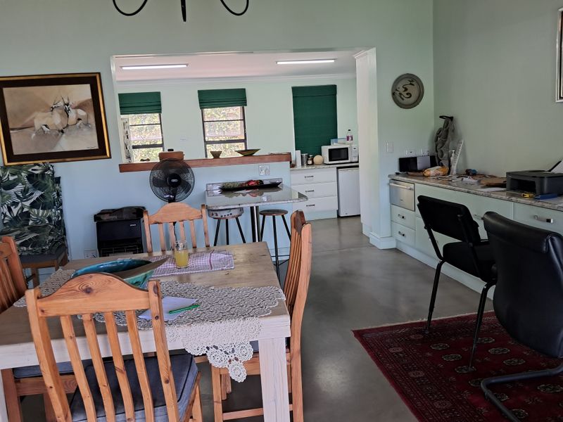 Open plan living and dining area featuring polished concrete floors, a functional kitchen with stone countertops, and a breakfast bar pass-through window.