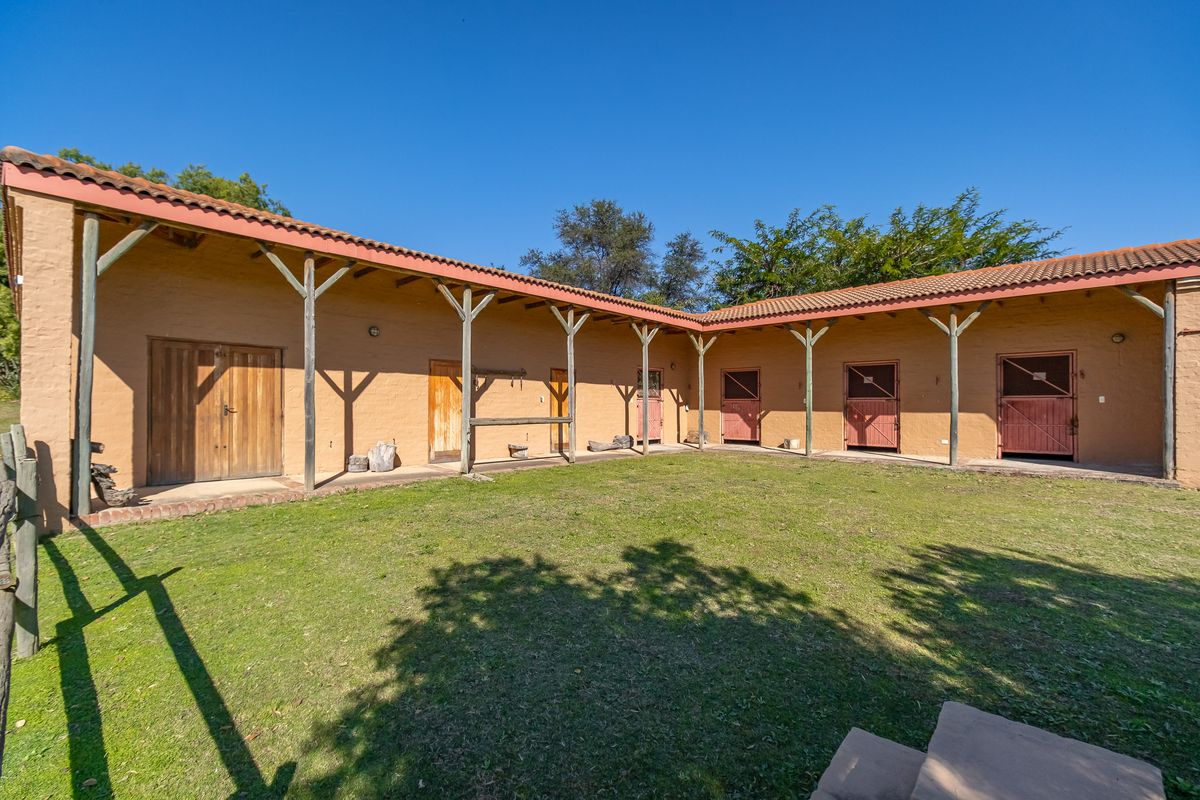 A well-maintained stable block featuring a central grass courtyard, covered walkways with timber supports, and multiple stable doors.