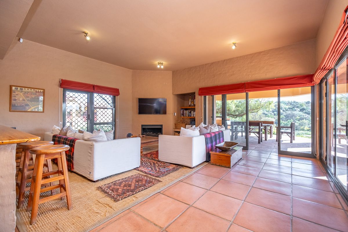 Spacious living room featuring terracotta floor tiles, a built-in fireplace, and large sliding glass doors providing seamless access to the outdoor patio area.