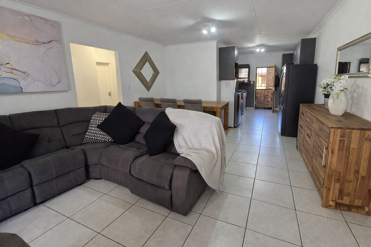 An open-plan living and dining area featuring neutral tiled flooring, modern kitchen cabinetry, and a seamless flow between the lounge and kitchen spaces.
