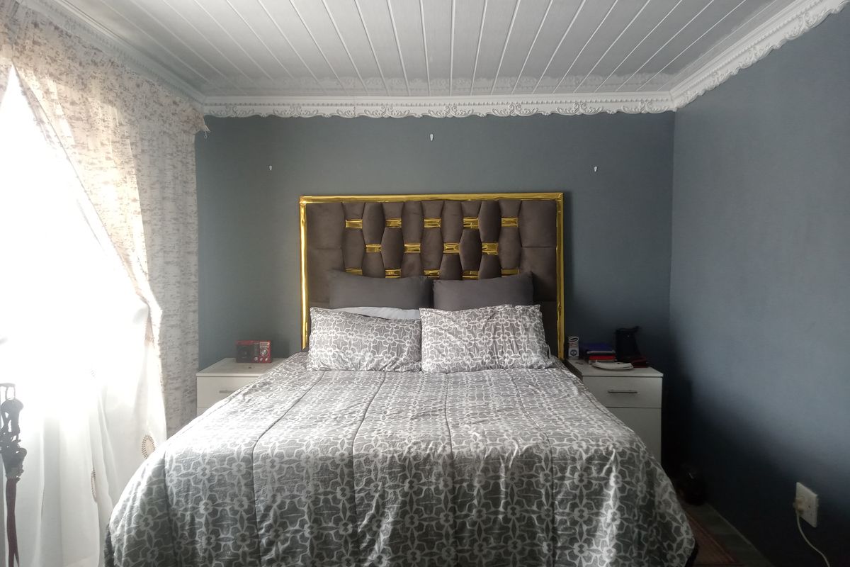 A bedroom featuring a decorative tongue-and-groove ceiling with ornate crown molding and grey painted walls.