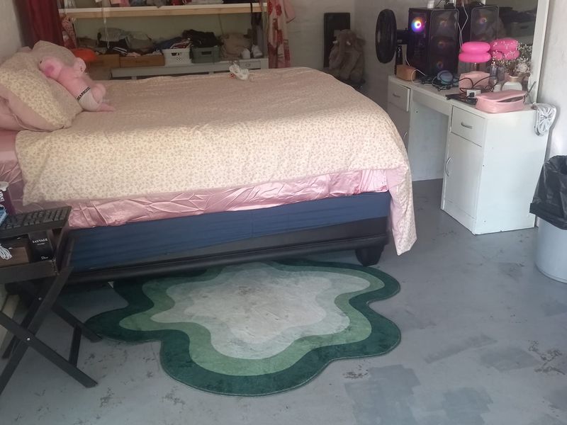 A bedroom featuring built-in shelving and an unfinished concrete floor, offering a functional space with potential for cosmetic updates.